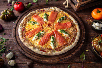 Tasty hot italian pizza Al salmon with Salmon, Philadelphia cheese, Mozzarella, Parsley, Sesame, Tomato Saucewith on old wooden table. Pizzeria menu. Concept poster for Restaurants or 