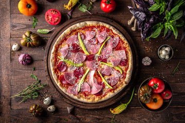 Tasty hot italian pizza with Bacon, Salami, Ham, Cheese Mozzarella, Parmesan, Peppers, Mushrooms, Pepperoni, Tomato Sauce on old wooden table. Pizzeria menu. Concept poster for Restaurants