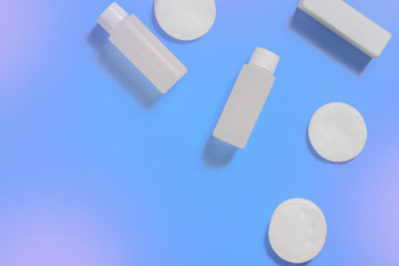 bottle for cosmetic products, cotton pads for cleansing, purple background