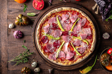 Tasty hot italian pizza with Bacon, Salami, Ham, Cheese Mozzarella, Parmesan, Peppers, Mushrooms, Pepperoni, Tomato Sauce on old wooden table. Pizzeria menu. Concept poster for Restaurants