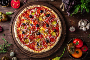 Tasty hot italian pizza Mexicana with Pork, Mozzarella, Pepperoni, Pickled Cucumbers, Olives, Tomatoes, Red Onions, Stewed Onions, Tomato Sauce  on old wooden table. Pizzeria menu. 