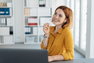 Smiling young businesswoman relaxing with music