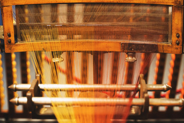Very old loom machine with colored threads.