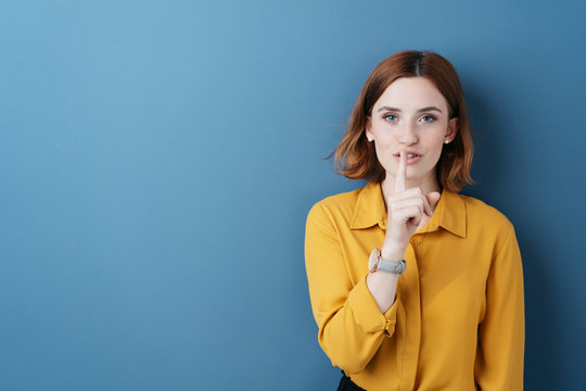 Attractive young woman making a shushing gesture