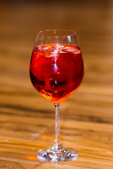 Misted glass. Spritz cocktail with ice. Orange drink in glass on wooden floor.