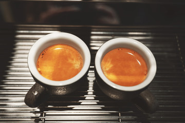 two cups of fresh made hot coffee espresso americano standing on professional coffee machine