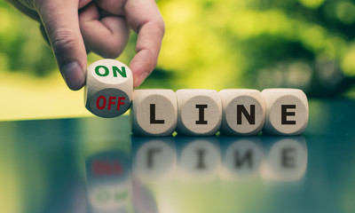 Hand turns a cube and changes the word "offline" to "online" (or vice versa).