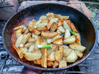 Cooking fried potatoes in outdoor conditions on fire.