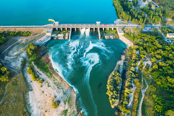 Aerial panoramic view of concrete Dam at reservoir with flowing water, hydroelectricity power...