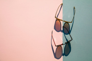 Fasionable summer sunglasses with long shadow on pink and blue background