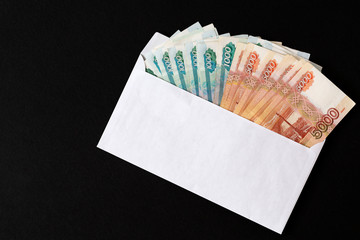 Envelope with ruble bills on black background. Bribe. Stack large ruble banknotes sticking out of...