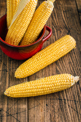 Fresh raw corn on the cob on a wooden background