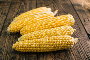 Fresh raw corn on the cob on a wooden background