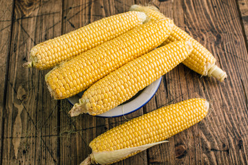 Fresh raw corn on the cob on a wooden background