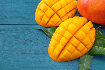 Fresh mango - beautiful chopped fruit with green leaves on dark blue timber background. Tropical...