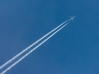 Airplane with condensation trail  in blue sky