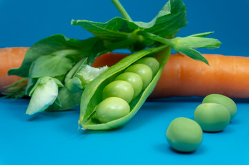 Pea pods carrot and peas on blue background