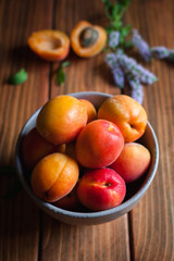 Close-up of apricots with fresh mint leaves and flowers on wooden background