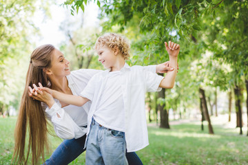 Fototapeta premium beautiful happy mother holding hands with adorable son in park