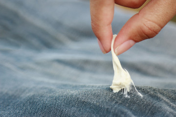 finger pulling gum sticking on jean fabric for cleaning 