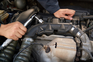 Fototapeta na wymiar A man holds the engine of a car with a torque wrench. Auto repair service and maintenance.