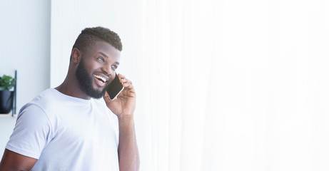 Cheerful african american guy talking on phone
