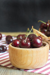 Close up of organic fresh sweet cherries in wooden bowl, farm fruits on farmer market table. Healthy food consept