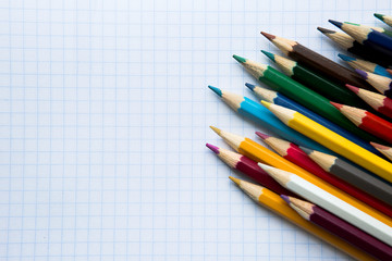Fototapeta premium colored pencils on an empty notebook, top view, space for text
