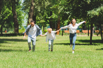 excited family holding hands and running in park during daytime