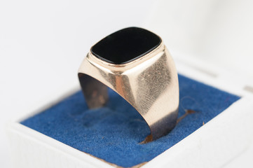 Male golden ring with black stone in a box isolated on a white background