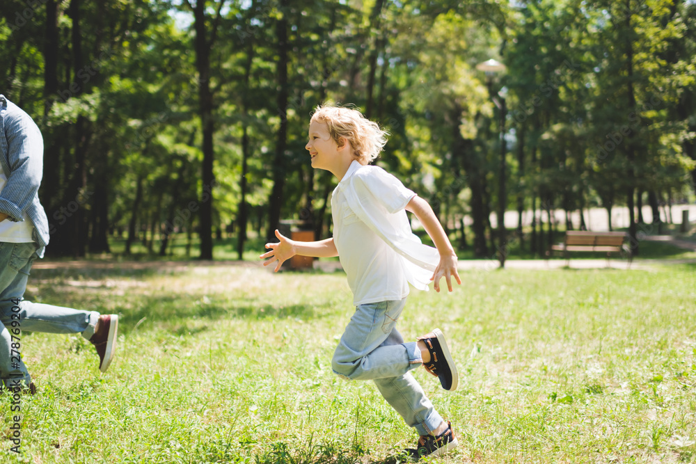 Wall mural happy son running with father in park during daytime