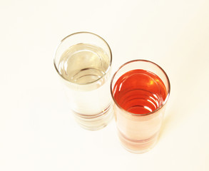 Two glasses of red and transparent liquid on white background, São Paulo, Brazil