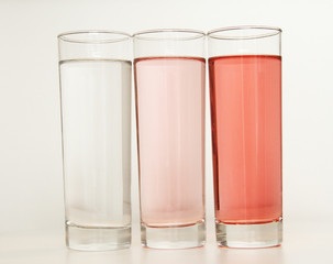 Three glasses of red and transparent liquid on white background, São Paulo, Brazil