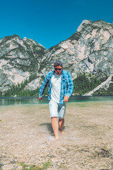 man walking by lake beach mountains on background with cold water