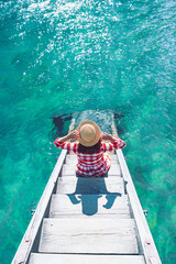 woman sitting on wooden stairs going to transparent clear water