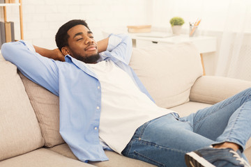 Handsome african-ameriacn man relaxing on sofa at home