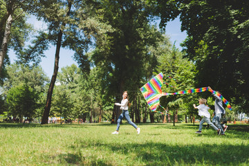 happy family running and playing with flying kite in park with copy space