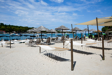 Armchairs with bamboo umbrellas and hammocks on sandy beach