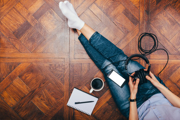 Top view of young female wearing jeans sitting on wooden floor
