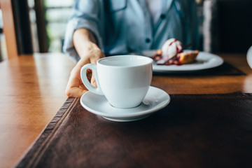 Female hand serves tea in cup on saucer