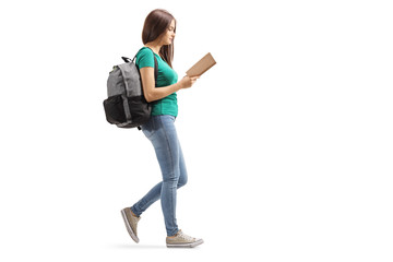 Fmale with a backpack reading a book and walking