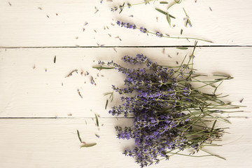 A field lavender bouquet is scattered on a white vintage table.
