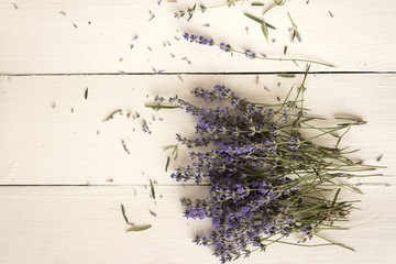 A field lavender bouquet is scattered on a white vintage table.