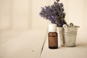 a glass jar with lavender oil is next to a small bouquet of flowers.