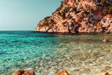 Idyllic empty beach spot with crystal clear turquoise water in the early morning light during...