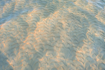 Soft wave of the water on the sandy beach. Waves of sand under the water