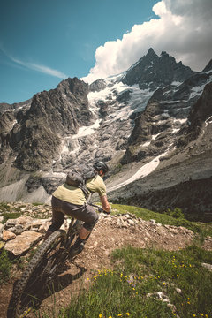 Mountain biker descending rough steep trail in the alps