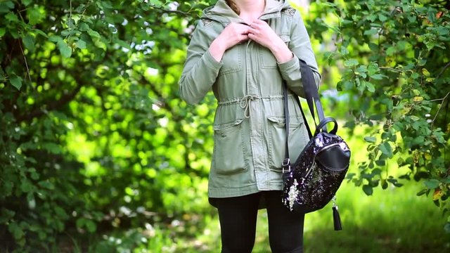 Girl buttons buttons. On her hand is a backpack.