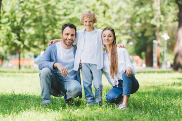 Fototapeta premium happy family looking at camera and hugging in park