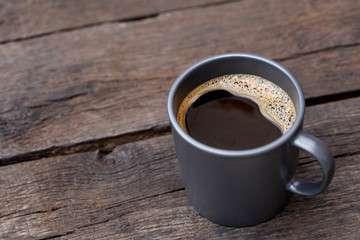 Black coffee in a blue-grey ceramic mug isolated on rustic dark brown wood table. Space for text.
